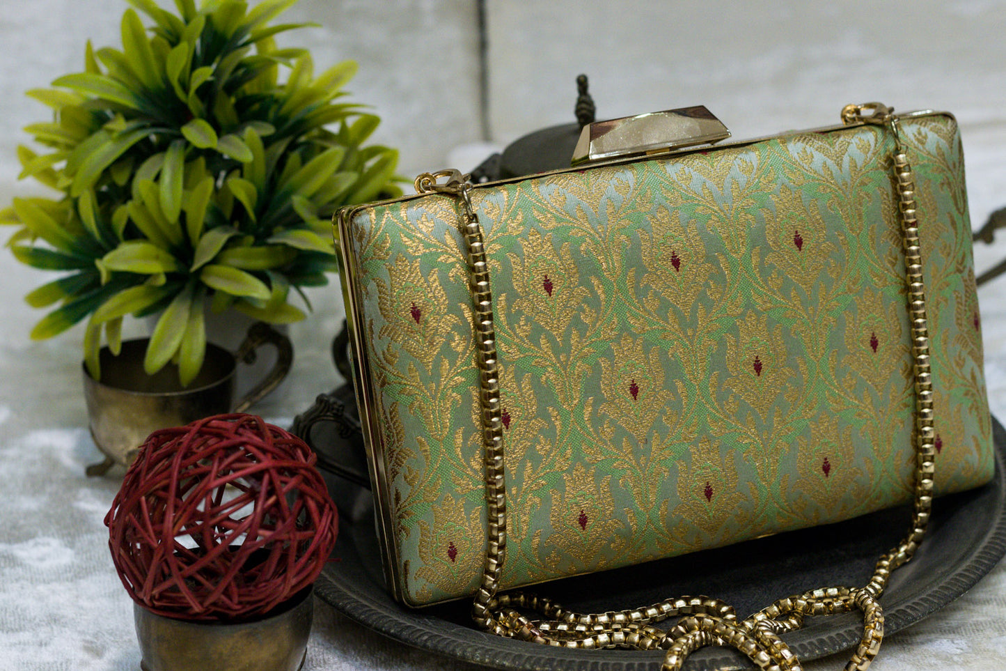 Aqua green Banarasi brocade clutch bag with traditional gold floral motifs and a gold chain strap, handmade design.