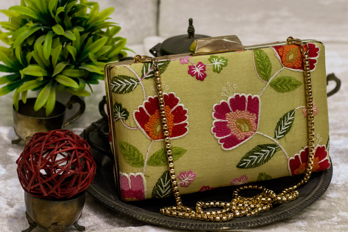 Light olive Banarasi brocade clutch bag with traditional floral embroidery and gold chain strap, handmade design.