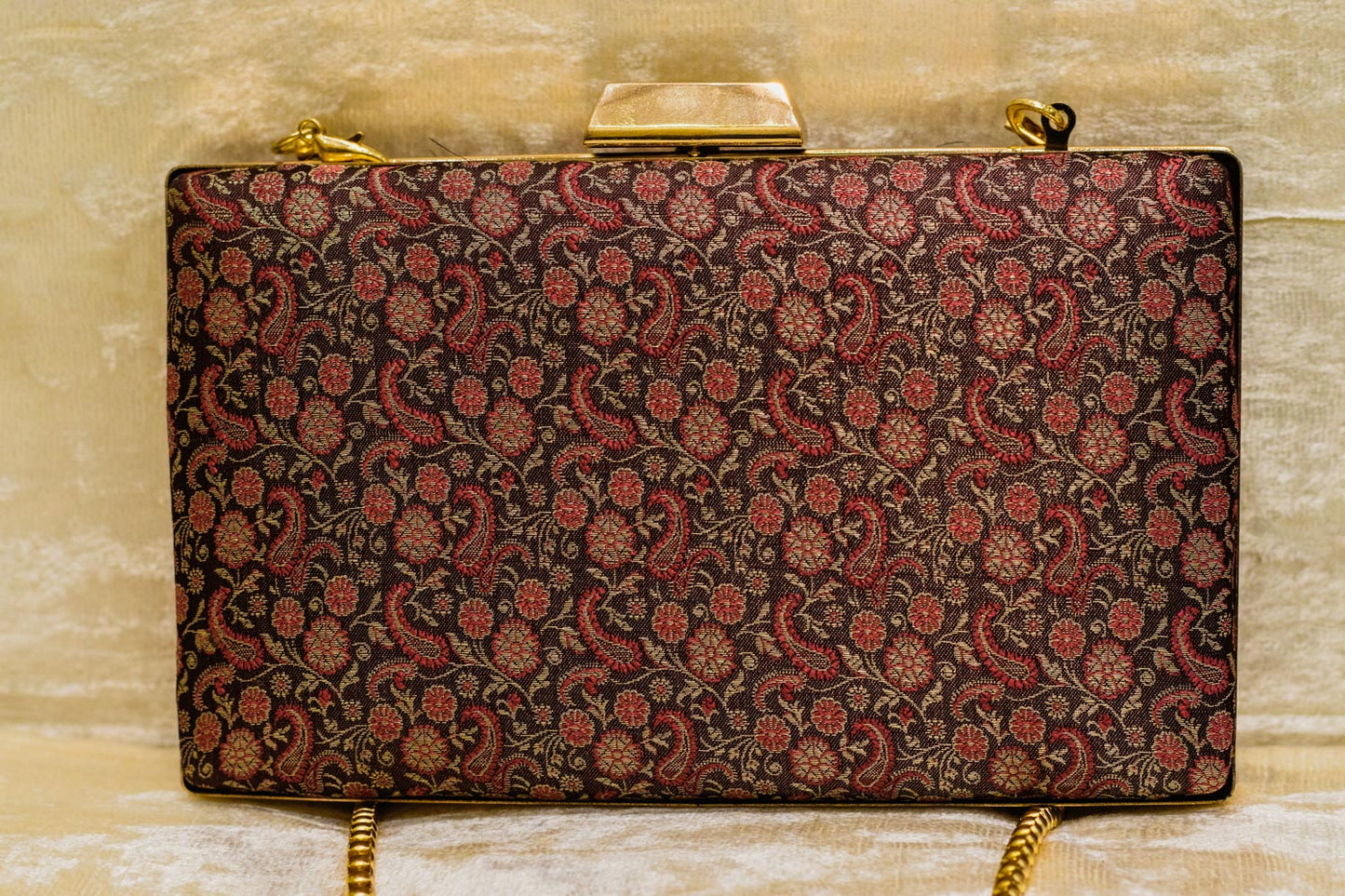 Wine-colored Banarasi brocade clutch bag with intricate traditional floral patterns and gold chain, handmade design.