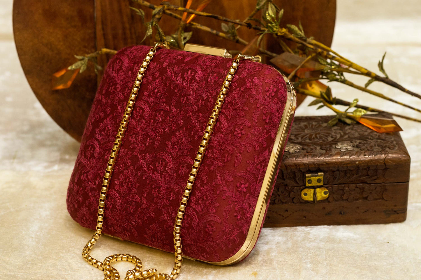 Maroon Banarasi brocade clutch bag with traditional handmade embroidery and gold chain strap.