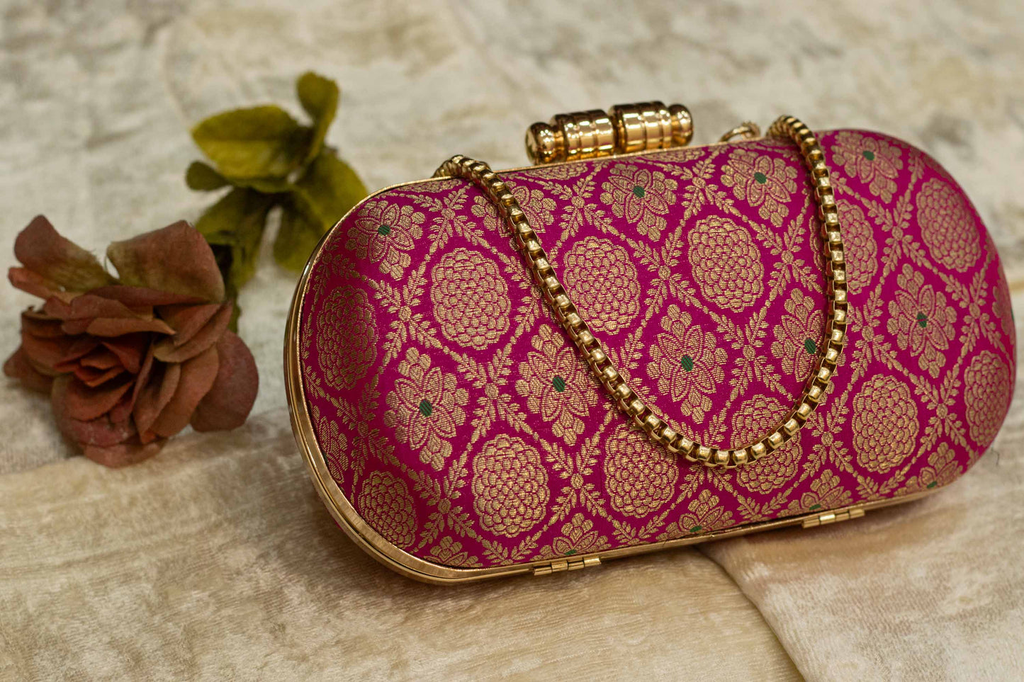 Rani pink Banarasi brocade clutch bag with gold chain and traditional handmade design.