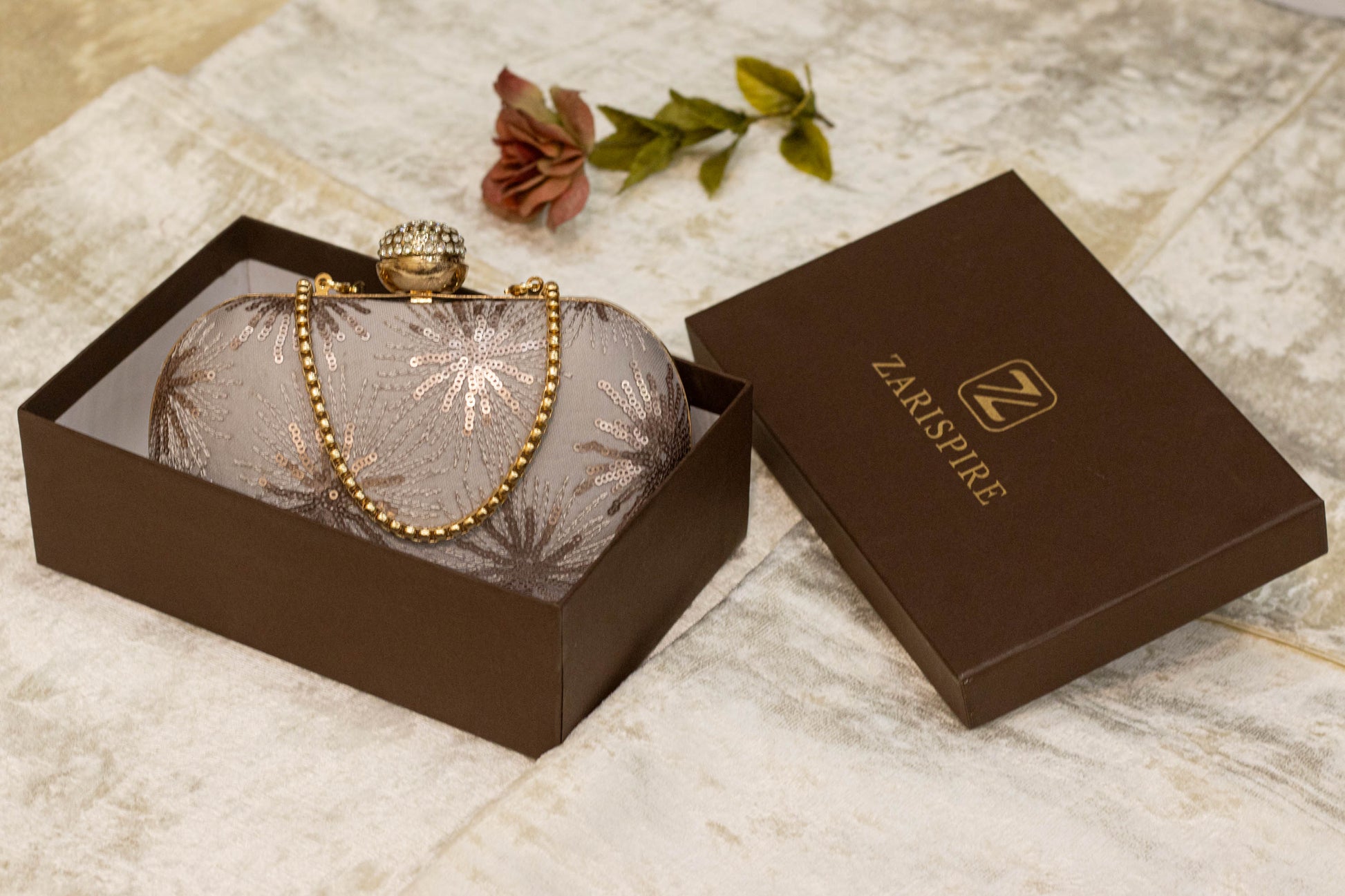 Lavender gray banarasi brocade clutch bag with gold chain and traditional handmade detailing in brown box.