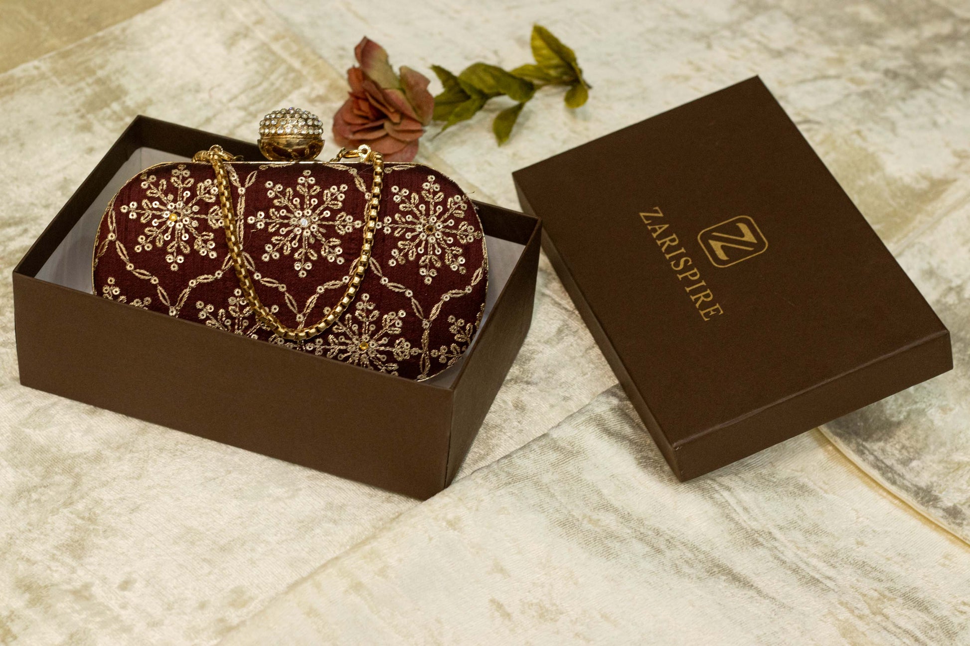 Maroon Banarasi brocade clutch bag with traditional gold floral embroidery, handmade design in gift box.