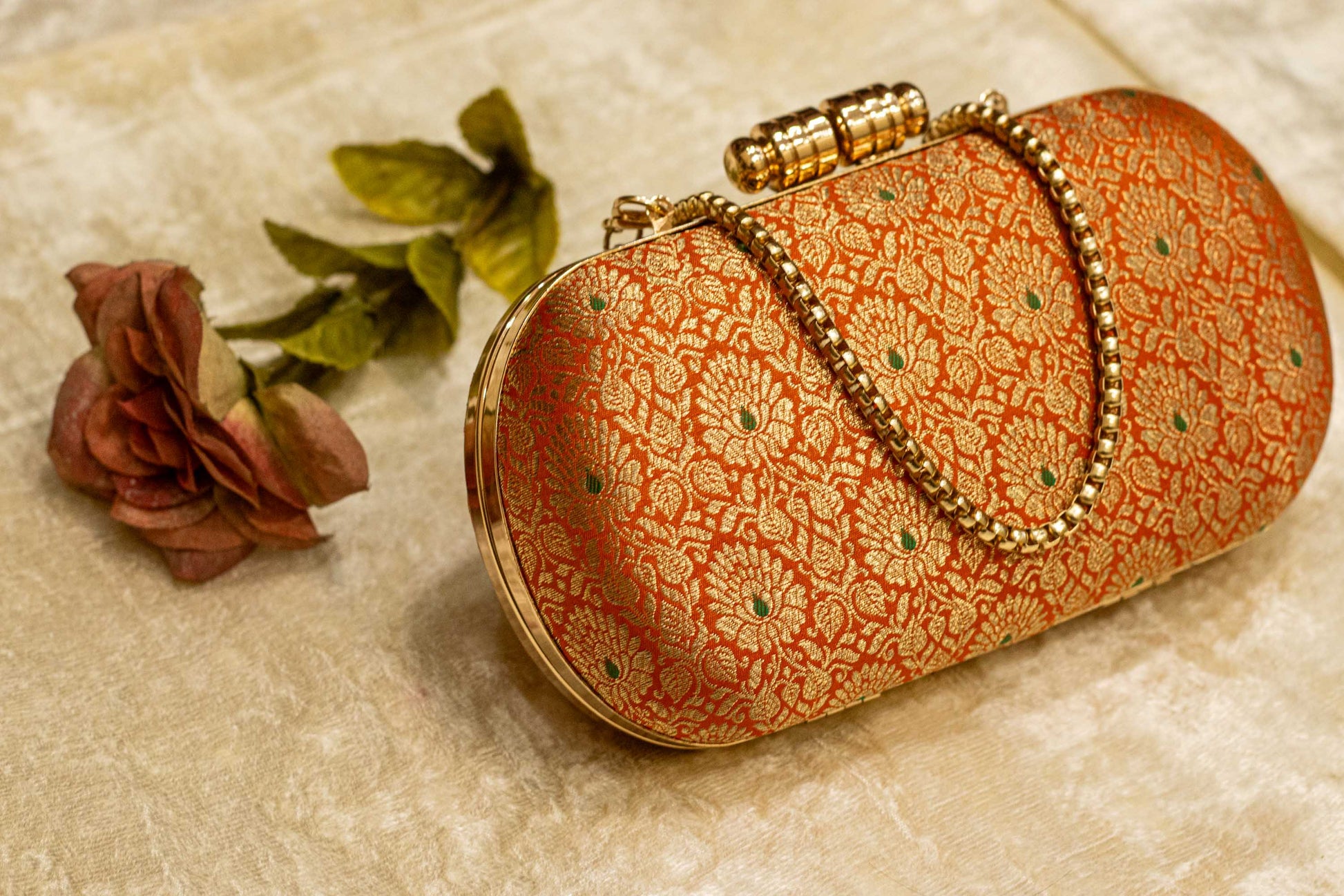 Saffron Banarasi brocade clutch bag with traditional floral pattern and handmade gold chain clasp.