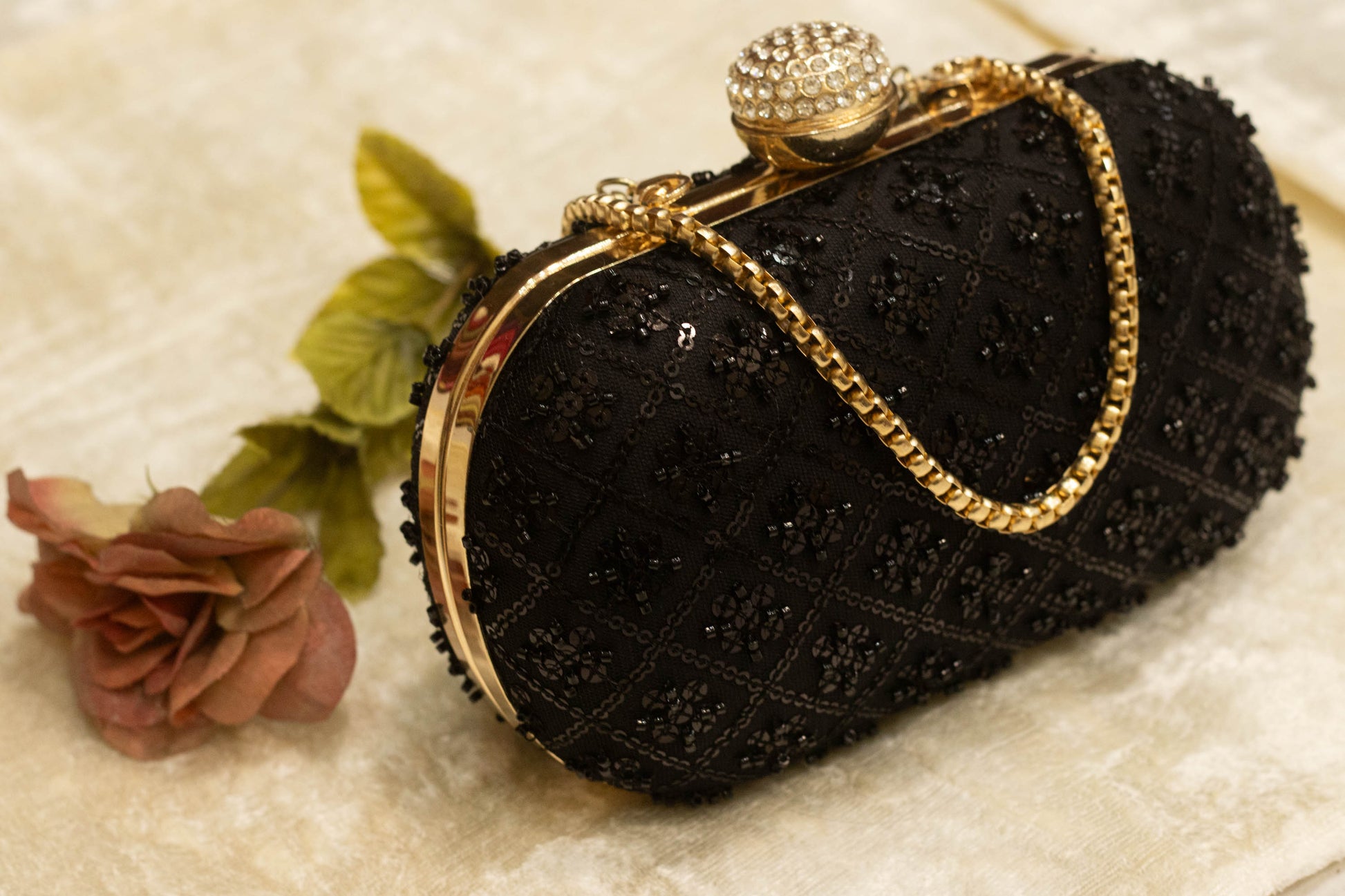 Black handmade Banarasi brocade clutch bag with gold clasp and chain strap, traditional design.