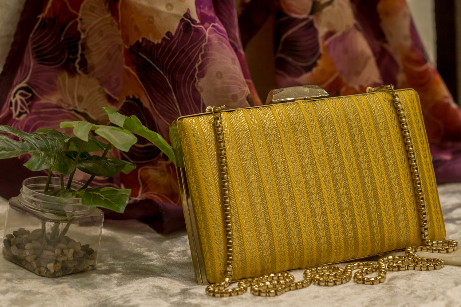 Yellow brocade Banarasi clutch bag with sleek striped texture and gold chain, handmade traditional clutches.