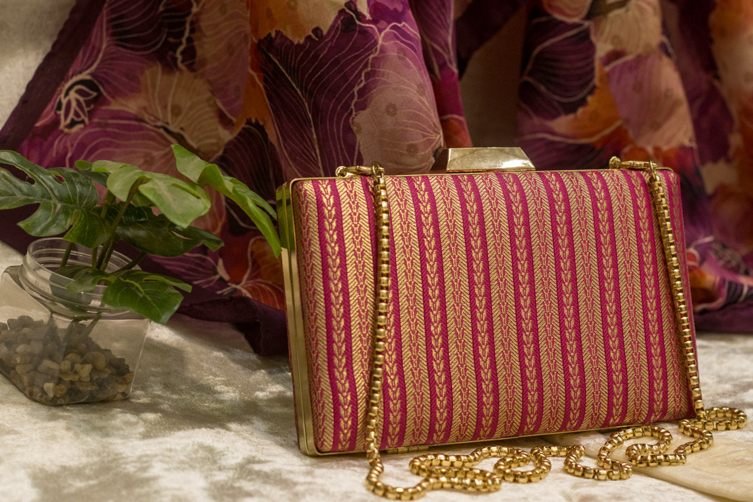Rani pink brocade Banarasi clutch bag with intricate gold stripes and a gold chain, traditional handmade clutches.