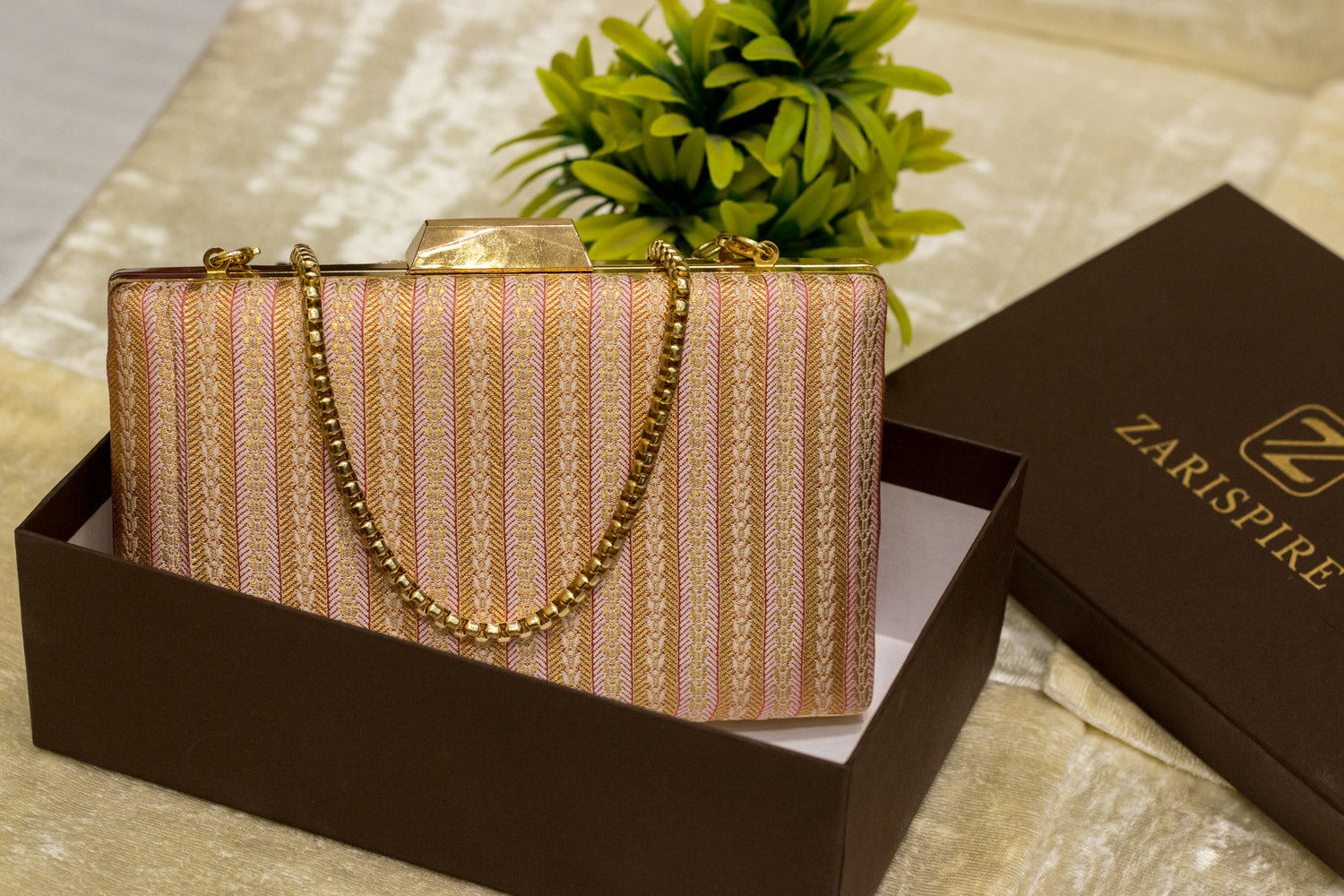 Baby pink Banarasi brocade clutch bag with gold chain, traditional handmade sleek design.