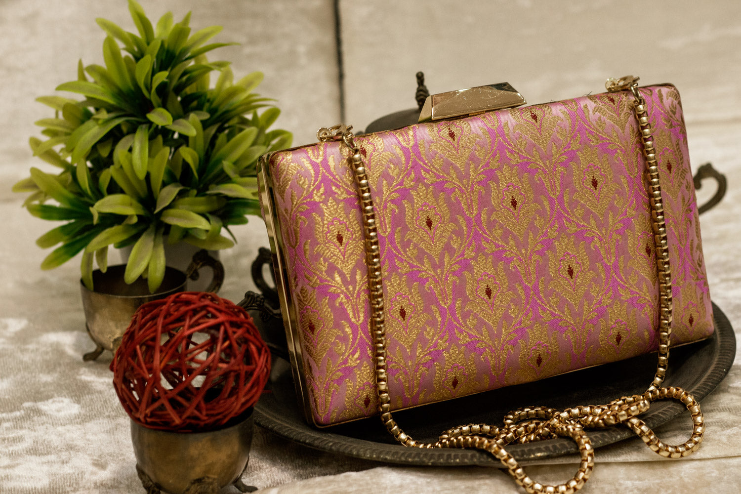 Pink Banarasi brocade clutch bag with traditional handmade floral patterns and gold chain strap.