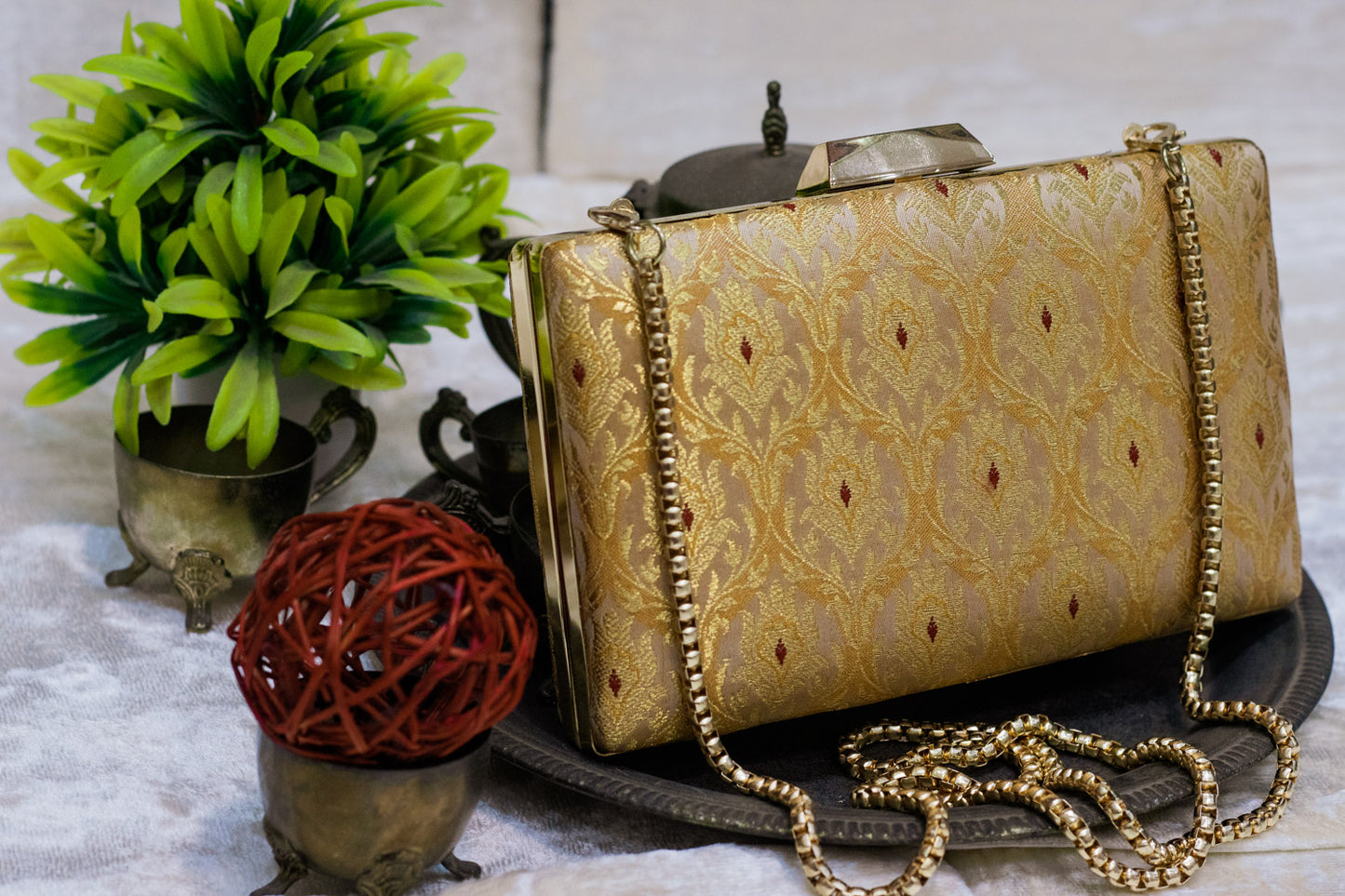 Traditional handmade banarasi brocade clutch bag in gold with intricate patterns and a delicate chain strap.