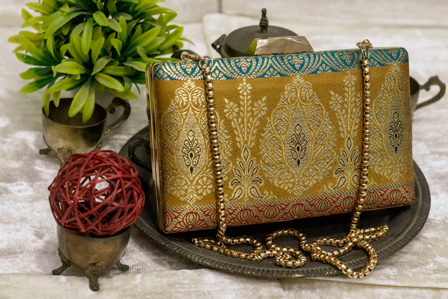 Traditional handmade Banarasi brocade clutch bag with gold and multicolor floral patterns and chain strap.