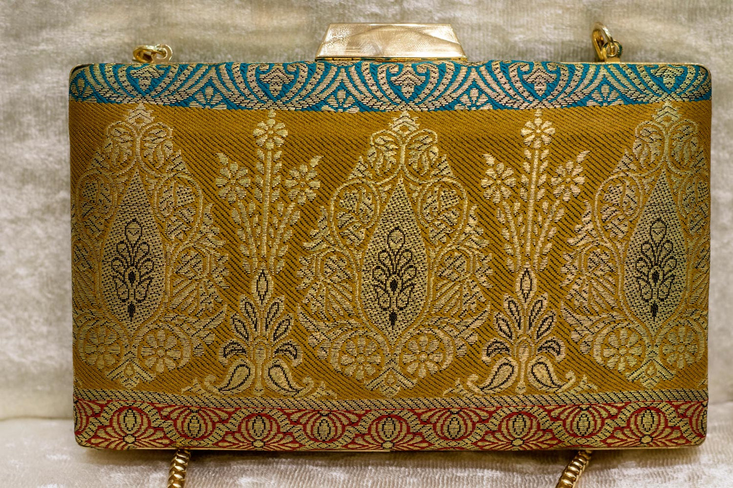 Banarasi brocade clutch bag in gold with teal and maroon detailing, traditional handmade design.