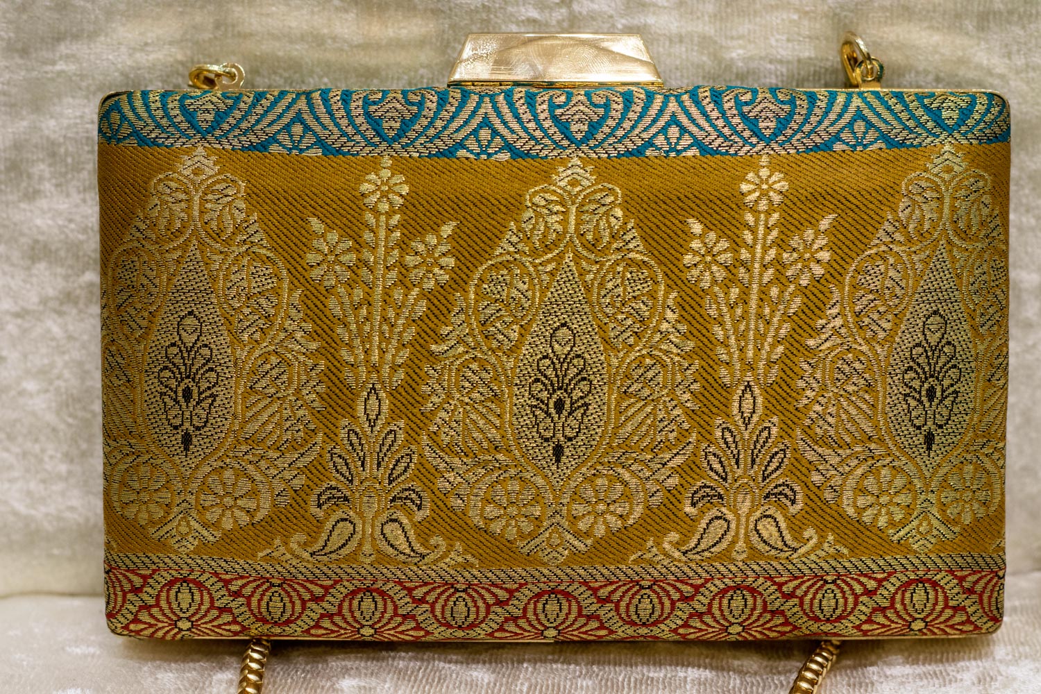 Banarasi brocade clutch bag in gold with teal and maroon detailing, traditional handmade design.