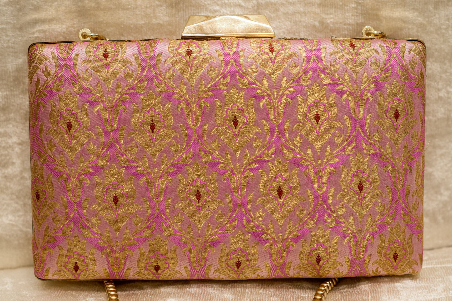 Pink Banarasi brocade clutch bag with traditional handmade gold patterns and a gold chain strap.