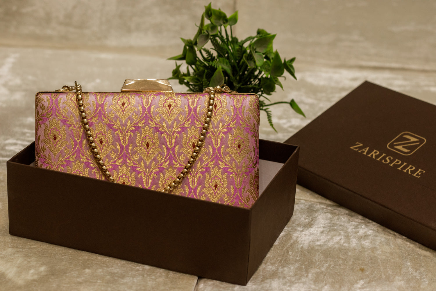 Pink Banarasi brocade clutch bag with traditional gold floral pattern, handmade with chain strap.