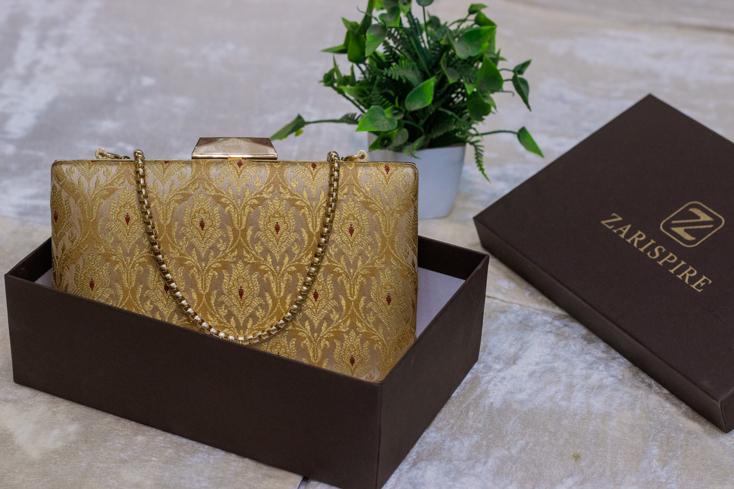 Gold Banarasi brocade clutch bag with intricate traditional embroidery, handmade design with gold chain strap.