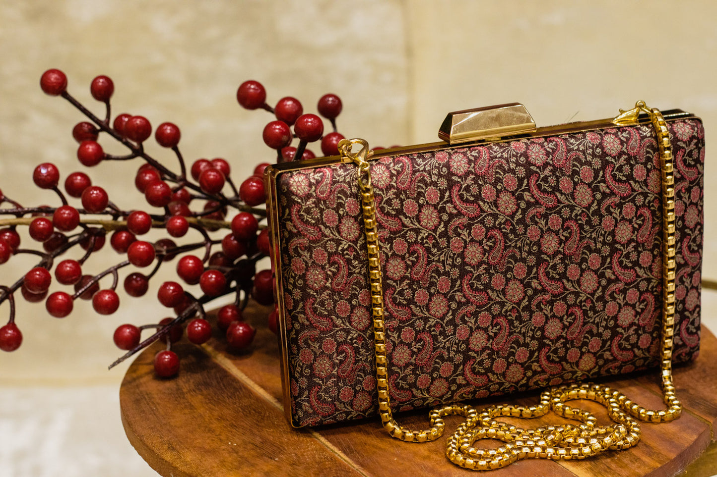 Wine-colored Banarasi brocade clutch bag with intricate traditional floral patterns and gold chain strap, handmade design.