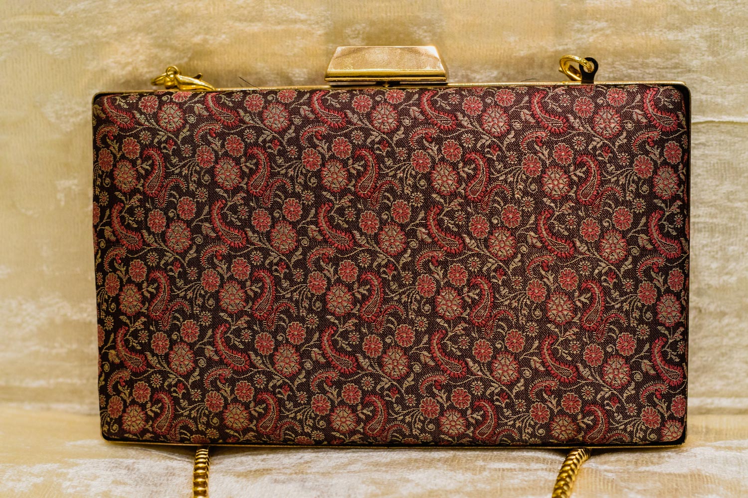 Wine-colored Banarasi brocade clutch bag with intricate traditional floral patterns and gold chain, handmade design.