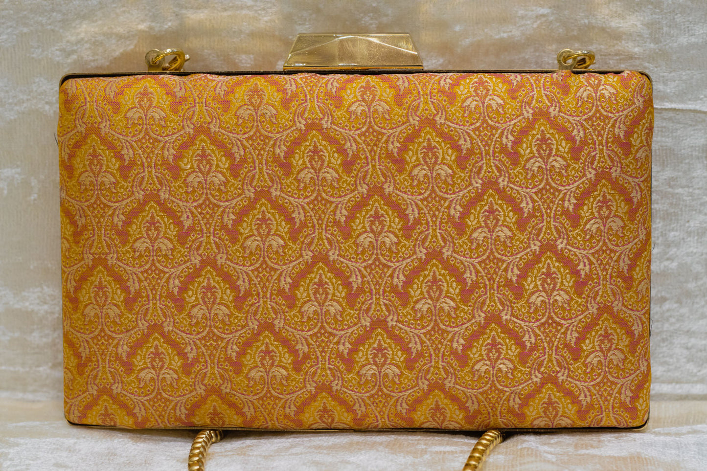 Yellow Banarasi brocade clutch bag with intricate traditional handmade patterns and gold chain strap.