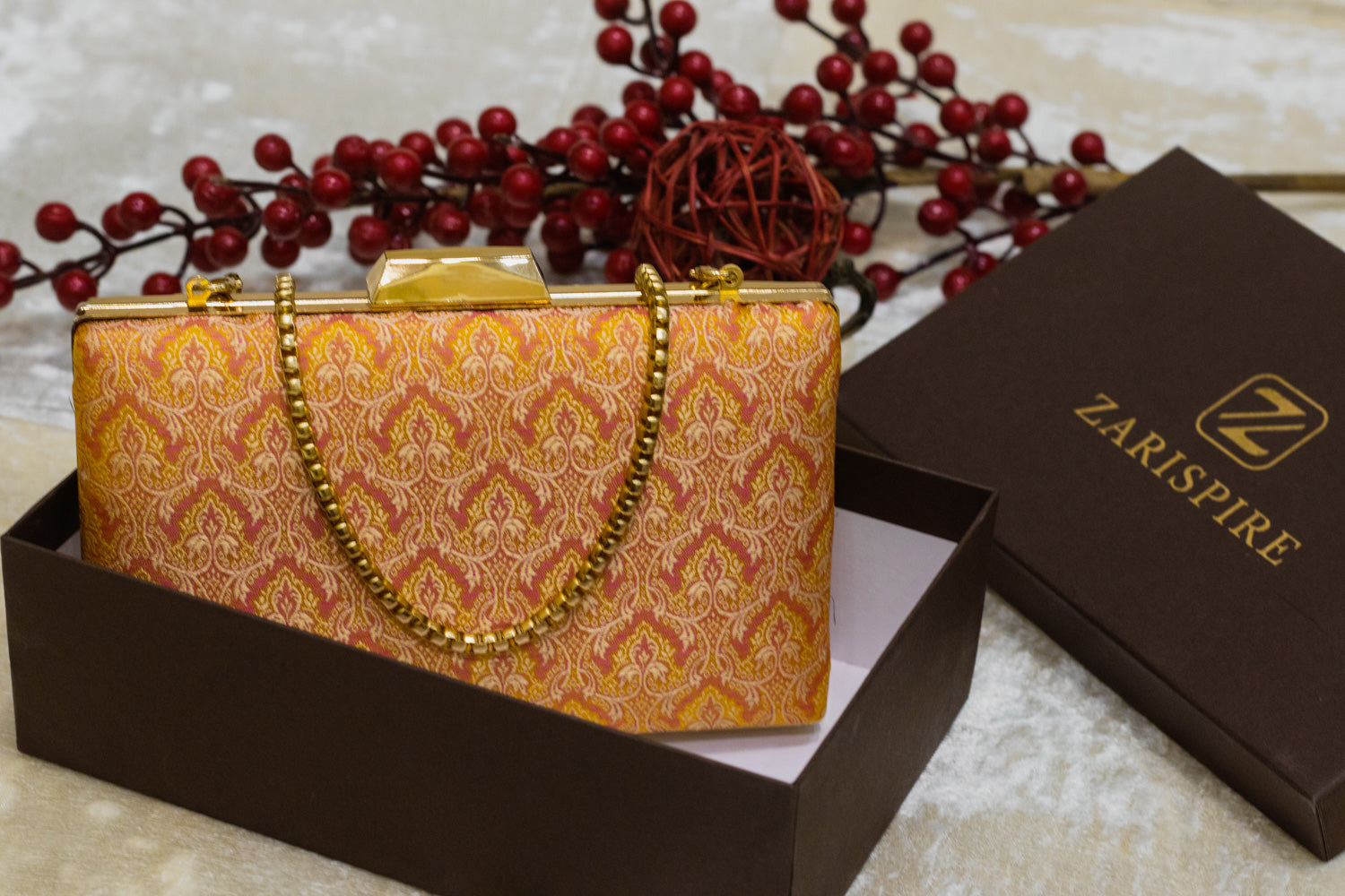 Yellow Banarasi brocade clutch bag with traditional handmade floral patterns and gold chain strap.