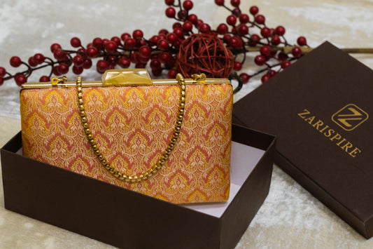 Yellow Banarasi brocade clutch bag with traditional handmade floral patterns and gold chain strap.