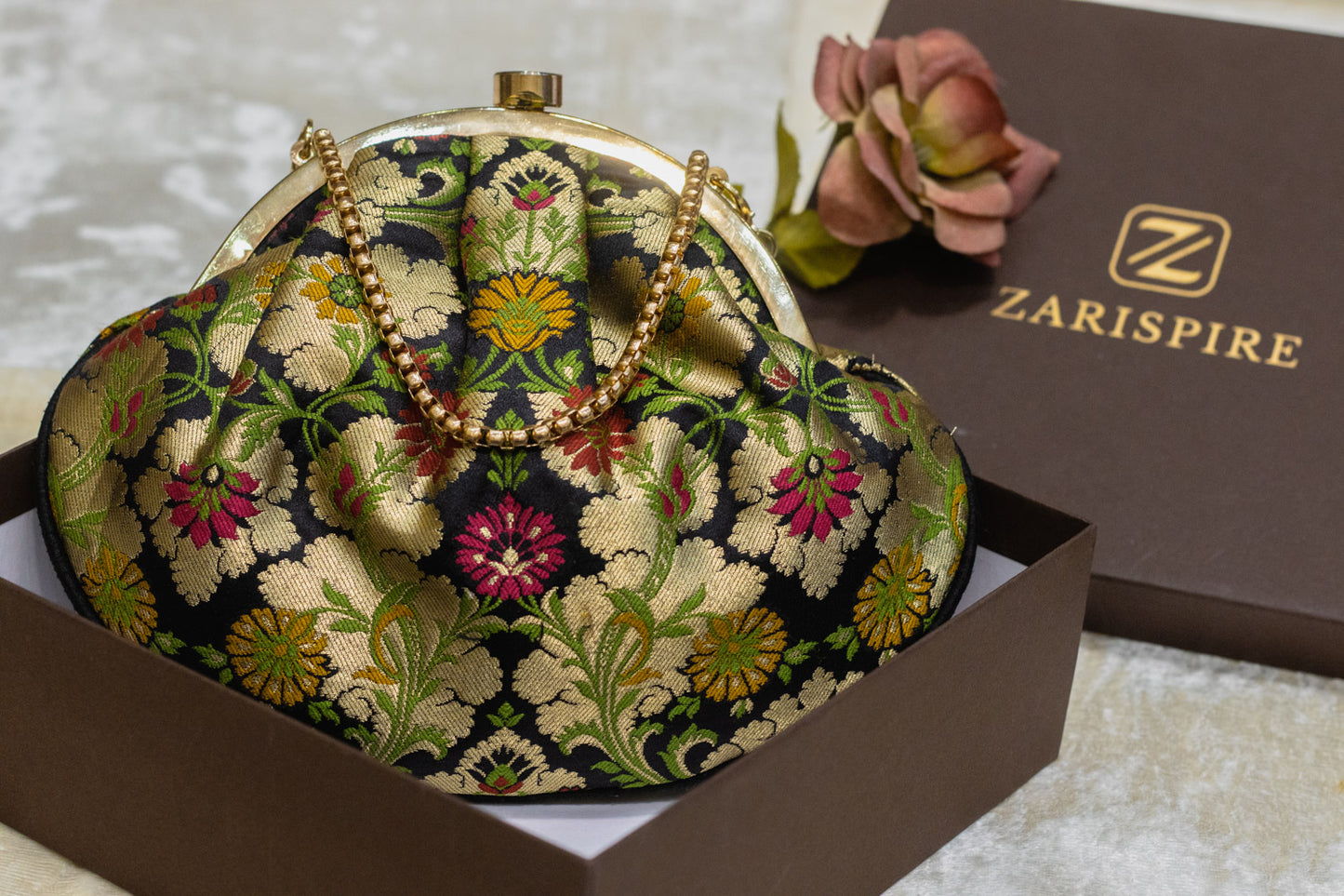 Black Banarasi brocade clutch bag with gold floral embroidery and traditional handmade design.