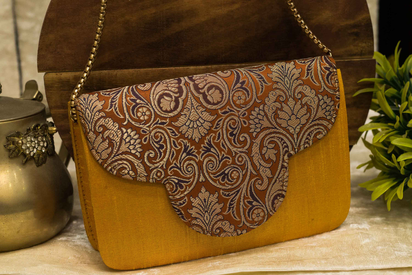 Orange handmade Banarasi brocade clutch bag with traditional intricate floral patterns and gold chain strap.