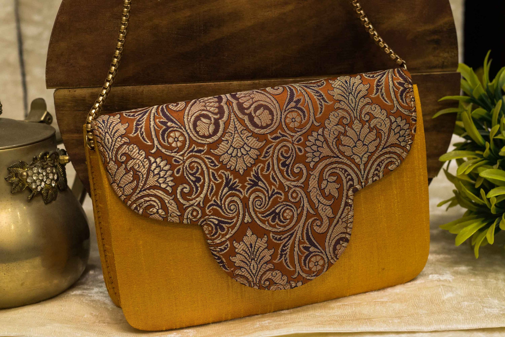Orange handmade Banarasi brocade clutch bag with traditional intricate floral patterns and gold chain strap.