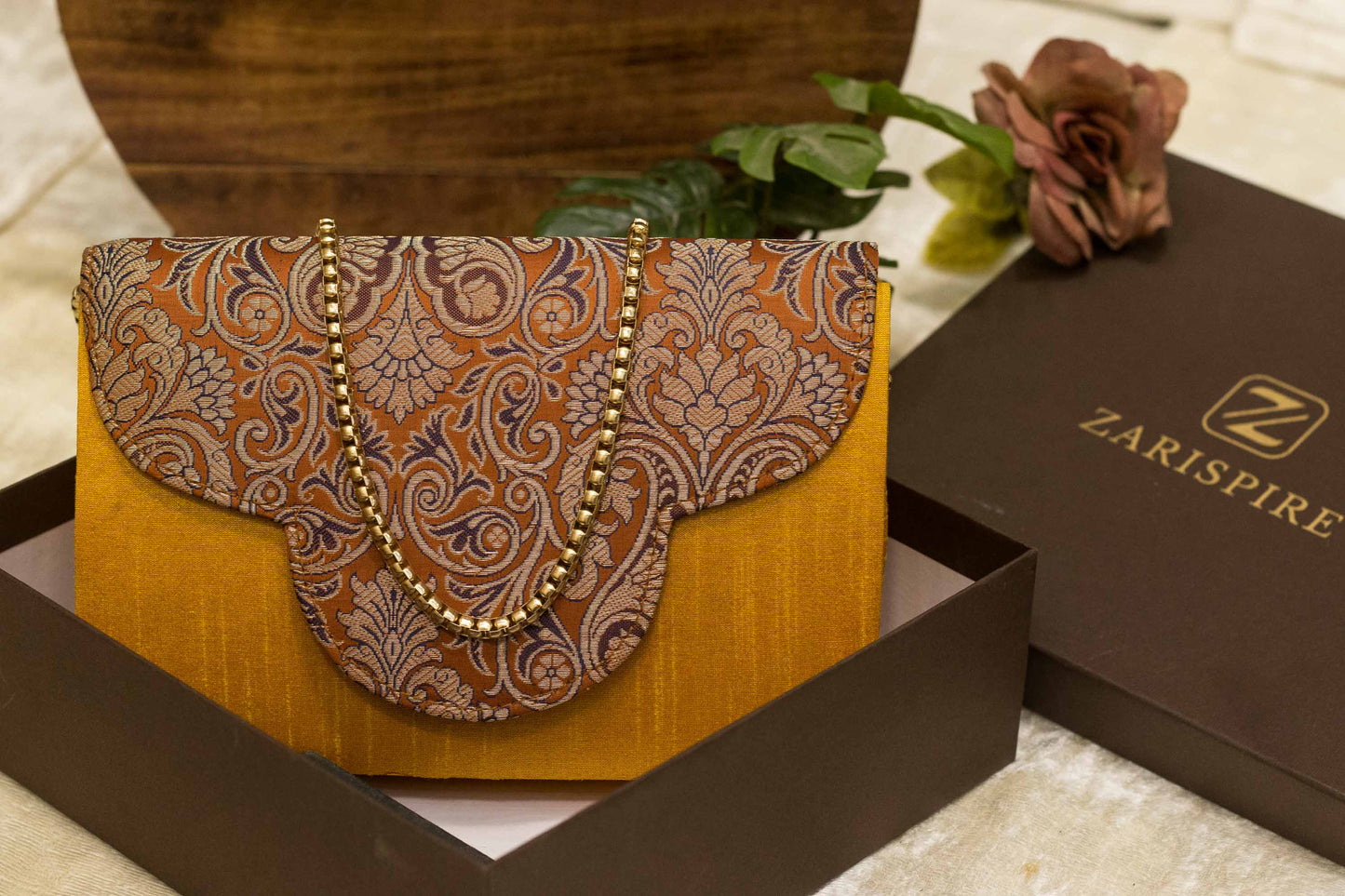 Orange Banarasi brocade clutch bag with traditional floral patterns, handmade Rajwada design.