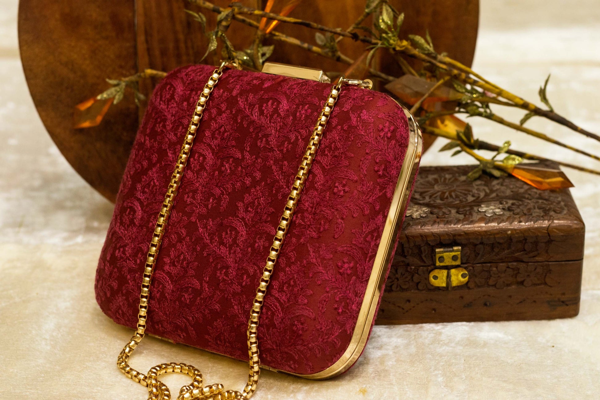 Maroon Banarasi brocade clutch bag with traditional handmade embroidery and gold chain strap.