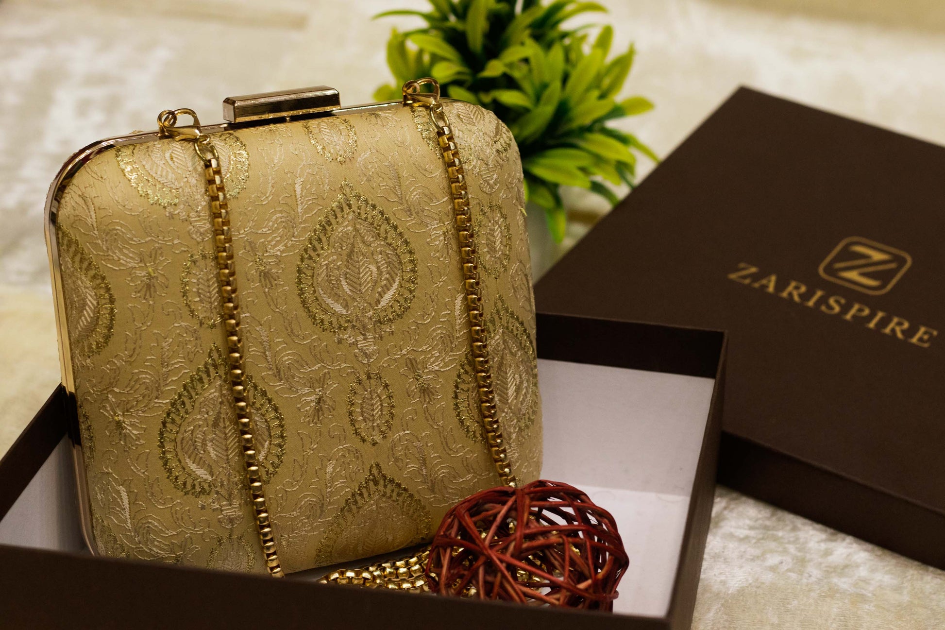 Square Banarasi brocade clutch bag in gold with traditional floral embroidery and gold chain, handmade design.
