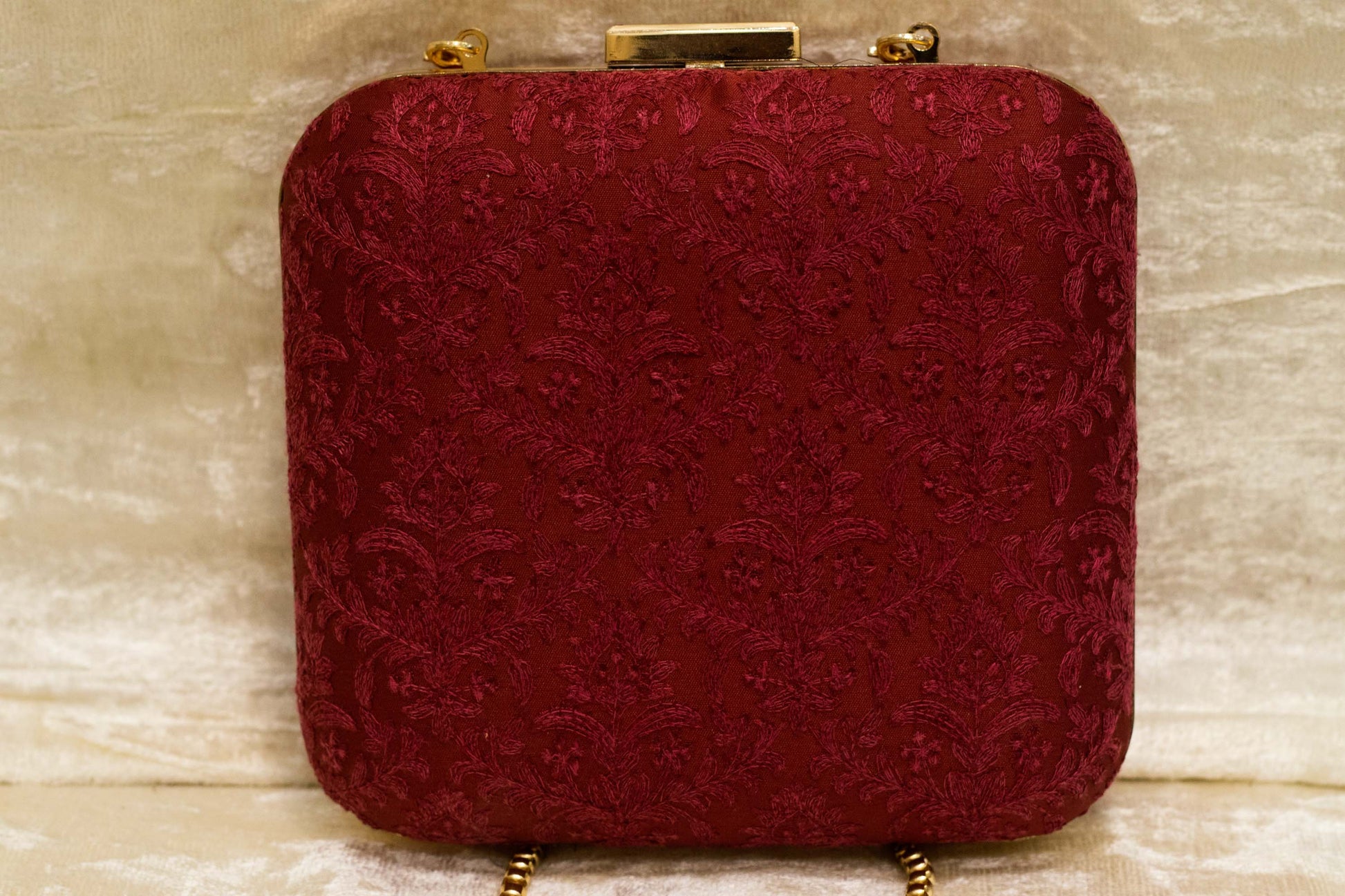 Maroon handmade Banarasi brocade clutch bag with traditional Chikankari embroidery and gold clasp closure.